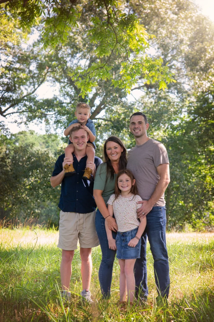 Hannah with her family outdoors beneath a tree